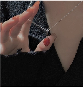 Macro shot of minimalist S925 silver necklace with vintage red oval stone pendant