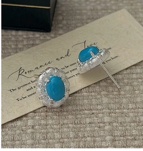 Macro detail of vintage S925 sterling silver turquoise stud earrings on beige fabric