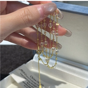 Détail d'un collier chaîne à billes dorées avec perles de cristal facettées et fermoir