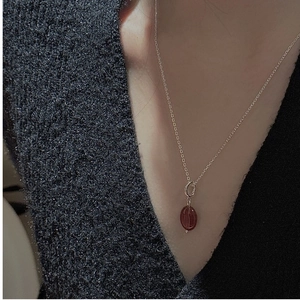 Close-up of minimalist S925 sterling silver necklace with a reddish-brown oval pendant