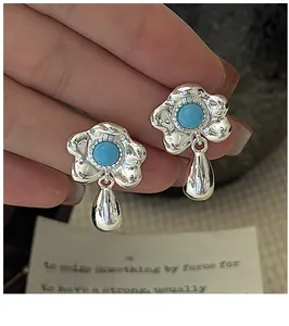 Macro detail of S925 silver flower earrings with turquoise stone and teardrop pendant