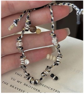 Close-up of S925 silver heart charm and woven fiber cord bracelet held by hand