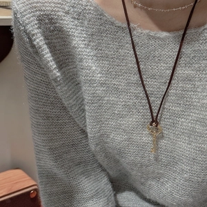 Retro S925 silver key pendant necklace with brown cord on a grey knit sweater