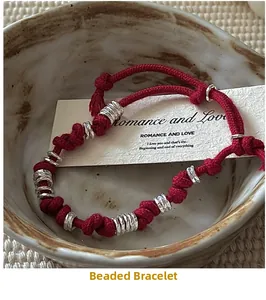 Macro detail of red woven bead bracelet with silver rings inside a ceramic bowl