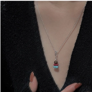 Close-up of S925 silver necklace featuring a trio of brown, red, and blue bead pendants