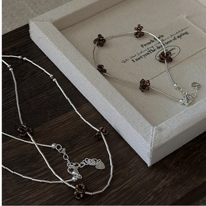 Macro shot of S925 sterling silver beads and heart tag with lobster clasp on vintage wood