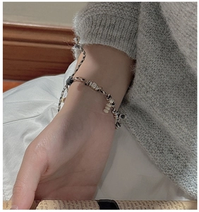 Detail of vintage woven rope bracelet with silver beads on wrist in home setting