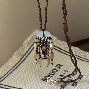 Bohemian style tassel necklace with coffee seed beads and shell drops on linen background