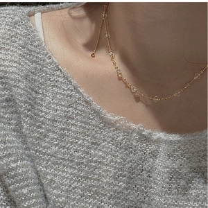 Détail d'un élégant collier ras du cou en cristal doré porté sur un pull gris