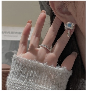 Close-up of S925 silver floral earring with blue turquoise and hammered texture ring