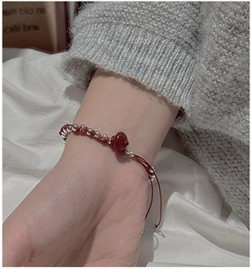 Close-up of red woven bracelet with silver beads and a central red agate stone