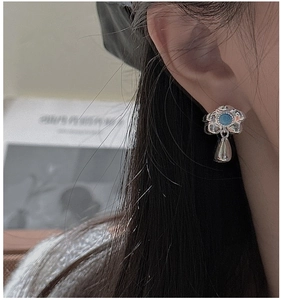 Detail of floral S925 silver earring with blue turquoise center and polished teardrop pendant