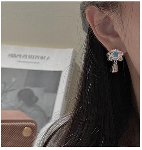Detail of silver flower drop earring with blue turquoise stone worn by a model