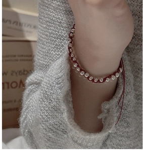 Close-up of red braided rope bracelet with silver beads on a model wrist
