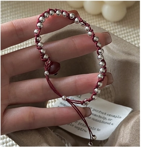Macro view of a handcrafted red braided rope bracelet with S925 silver beads and red agate