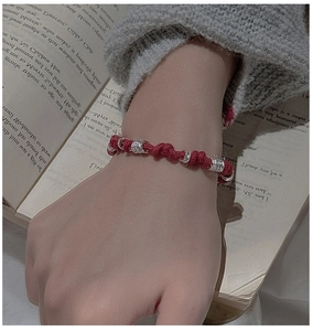 Macro detail of red spiral braided cord bracelet with silver beads on a wrist