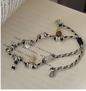 Detailed view of S925 sterling silver beads and woven ethnic rope bracelet on a book