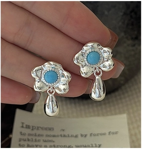 Macro shot of silver flower earrings with turquoise stone and metal teardrop pendant