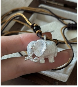Close-up of elephant pendant with brushed silver finish on a woven cord