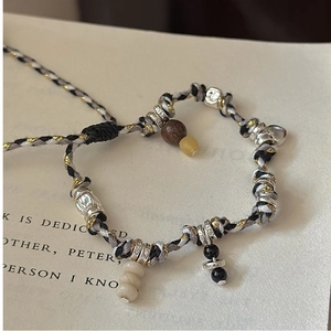 Detail of S925 silver charms and wooden beads on a handcrafted woven cord bracelet