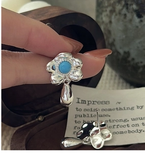 Macro view of S925 silver flower earring with blue turquoise and metal teardrop