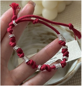 Close-up of red braided rope bracelet with S925 silver rings and tassel detail