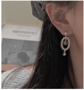Détail de boucles d'oreilles perles vintage avec cadre ovale sur un mannequin