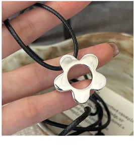 Detailed macro view of S925 silver flower pendant on a black woven cord necklace