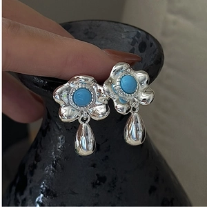 Macro detail of S925 silver flower earrings with turquoise stones and water drop pendants