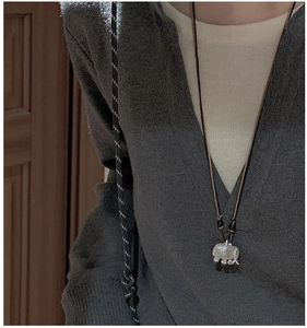 Detail of retro elephant pendant with brushed silver finish on brown woven cord necklace