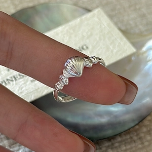 S925 sterling silver shell ring worn on finger with shimmering pearlescent background