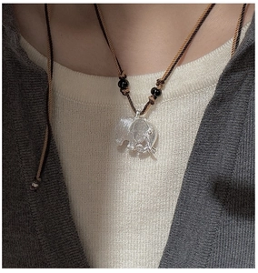 Close-up of a vintage brushed silver elephant pendant on a brown braided cord necklace