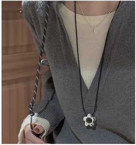Close-up of S925 silver flower pendant with black cord necklace worn on a female model