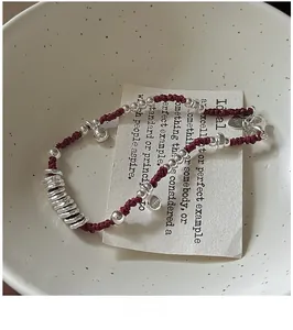 Dettaglio di perline in argento S925 e bracciale in corda rossa con incisione del marchio