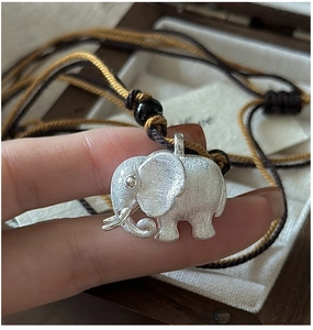 Macro detail of brushed S925 sterling silver elephant pendant on a braided rope