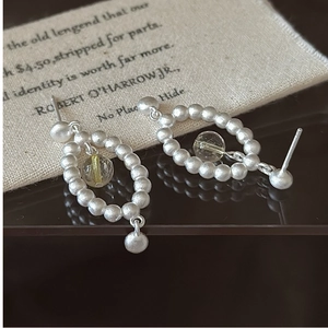 Détail des boucles d'oreilles ovales en argent S925 avec texture mate et perle jaune