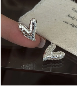 Détail macro de boucles d'oreilles cœur en argent S925 avec texture géométrique CNC
