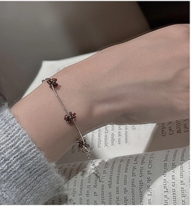 Detail of beaded brown flower charms on silver chain bracelet over vintage book