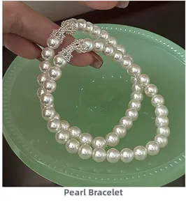 Détail du bracelet en perles avec breloques nœuds en strass scintillants tenu dans la main