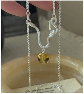 Detail of S925 silver necklace with abstract pendant and yellow crystal bead