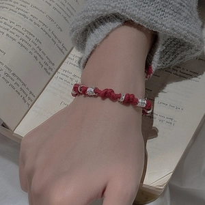 Minimalist red cord bracelet with silver spiral beads worn over a soft knit sleeve