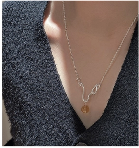 Detail of S925 silver necklace featuring amber crystal on black knit sweater texture