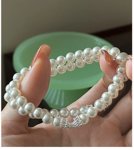 Détail du bracelet en perles double rang avec un fermoir en forme de nœud brillant