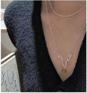 Close-up of triple layered S925 silver necklace with brown crystal pendant on black sweater