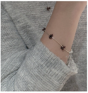S925 sterling silver beaded bracelet with dark red floral accents on a gray knit sleeve