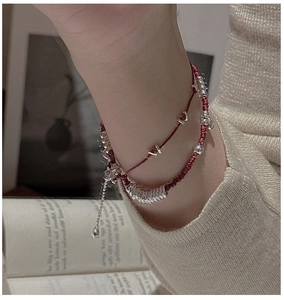 Dettaglio di un bracciale minimalista a doppio strato in corda rossa con perle d'argento