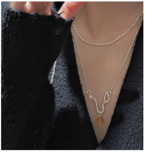Detail of S925 silver double layer necklace with amber crystal bead on black knitwear
