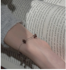 Detailed view of silver beaded flower bracelet worn with a vintage grey knit sweater