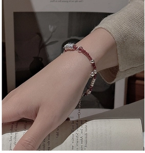 Dettaglio macro del bracciale in corda rossa con perle d'argento sul polso di un modello