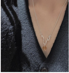 Macro detail of a S925 sterling silver wavy necklace with amber citrine pendant